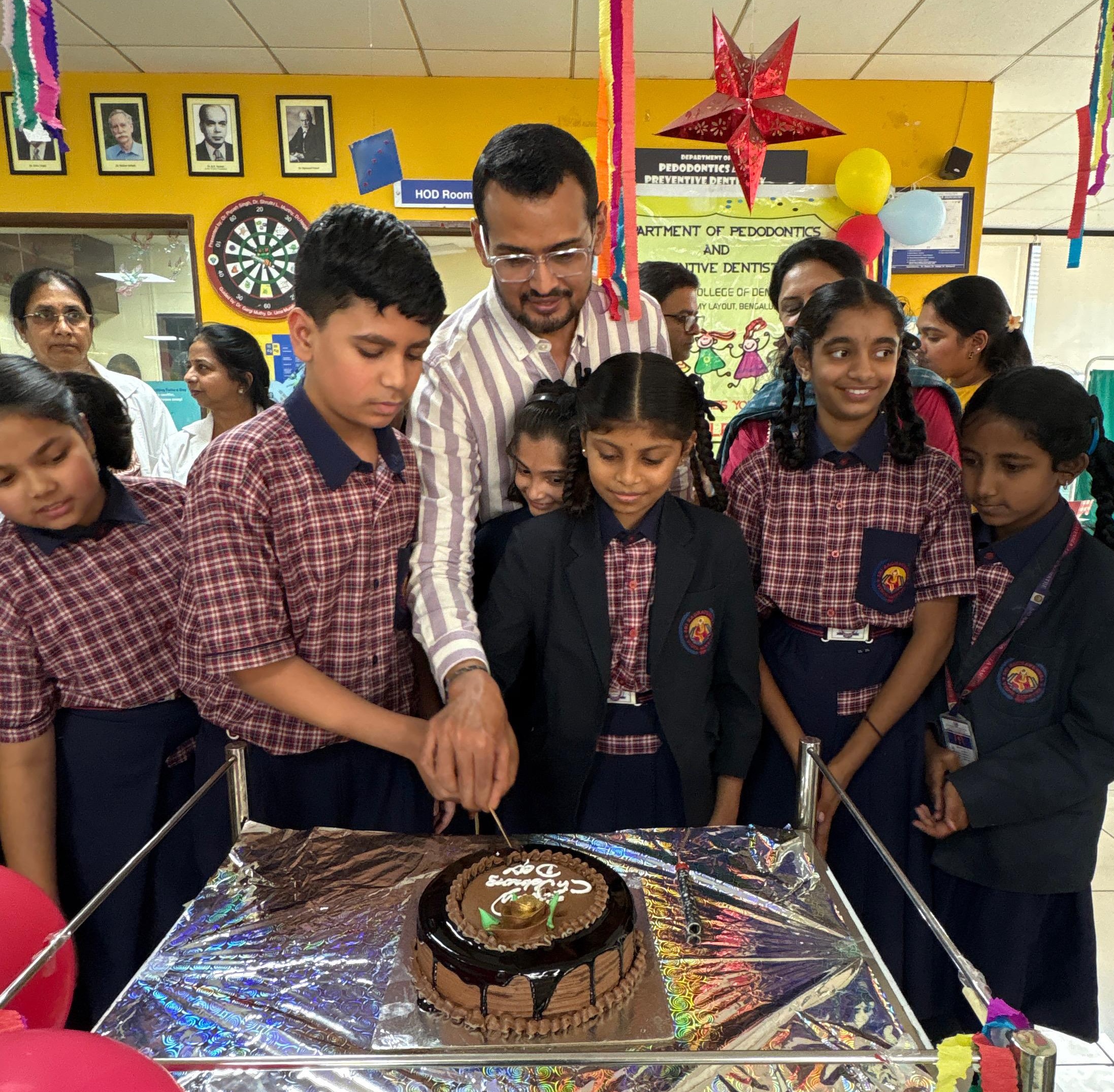 Faculty member and students cutting a cake for Children's Day